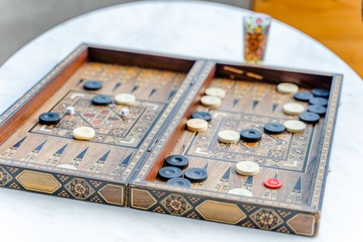 Wooden backgammon set on a marble table with drink in Dubai.