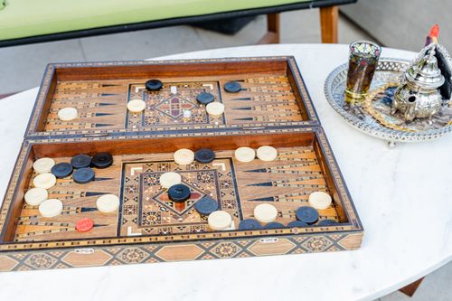Free Intricate backgammon board and Moroccan tea set on a marble table, showcasing Middle Eastern culture. Stock Photo
