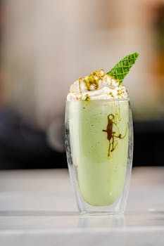 Enjoy a refreshing matcha latte topped with whipped cream and garnish, perfect for beverages and food photography.