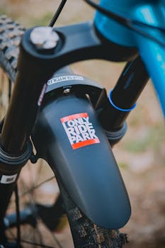 Detailed close-up of a mountain bike's front mud guard with a sticker, showcasing outdoor adventure gear.