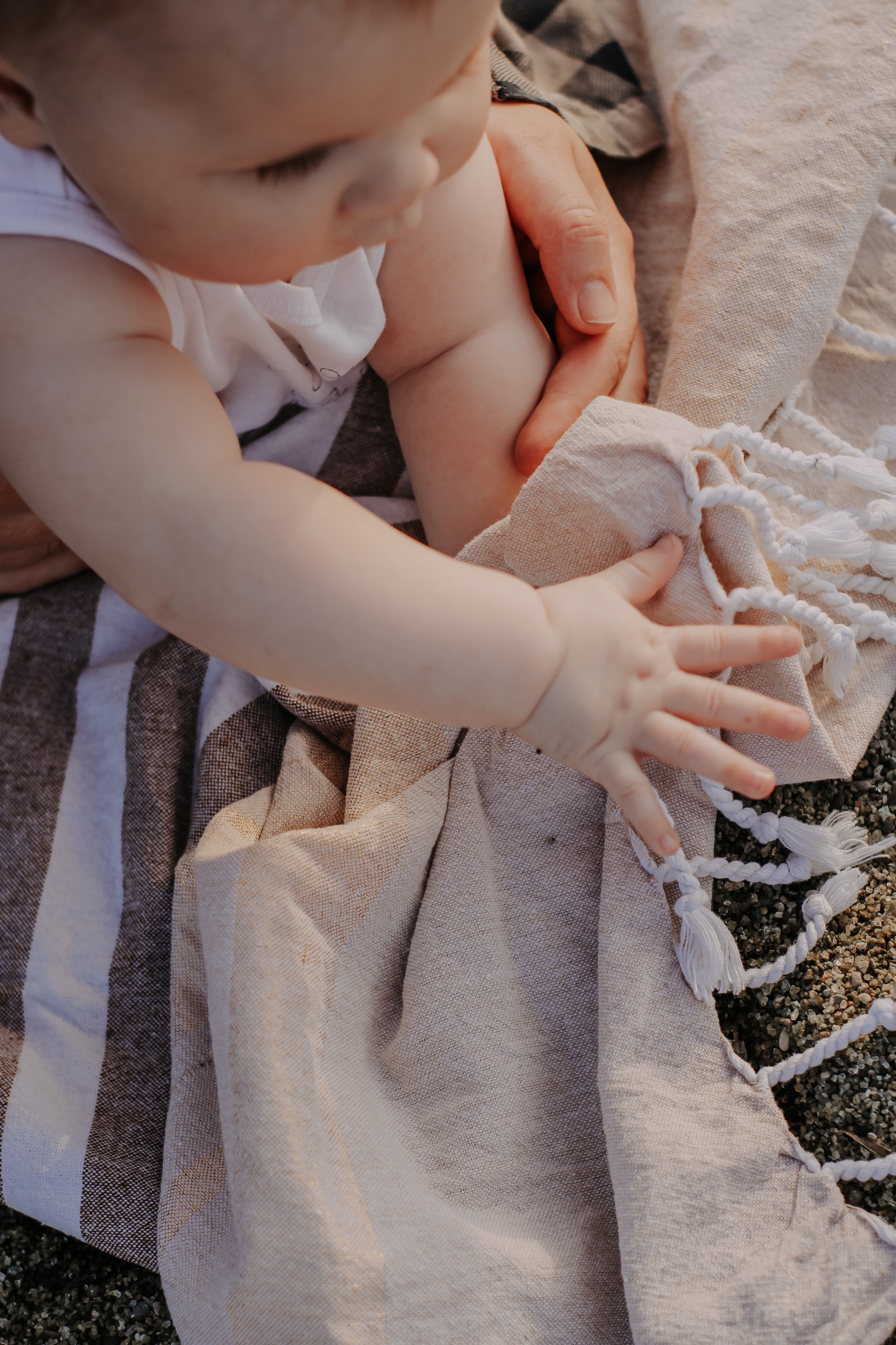Close-up of a baby's hand reaching for a parent's hand outdoors, symbolising the tender bond between caregiver and child