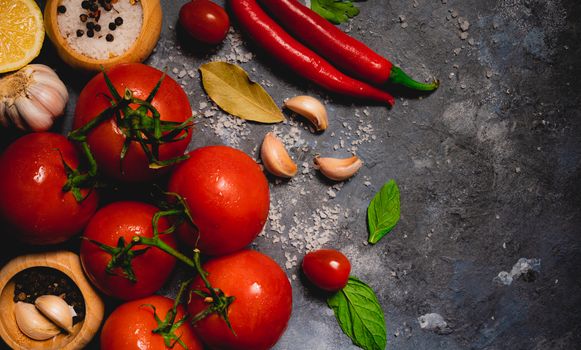A vibrant collection of fresh tomatoes, chili peppers, and herbs on a rustic surface.
