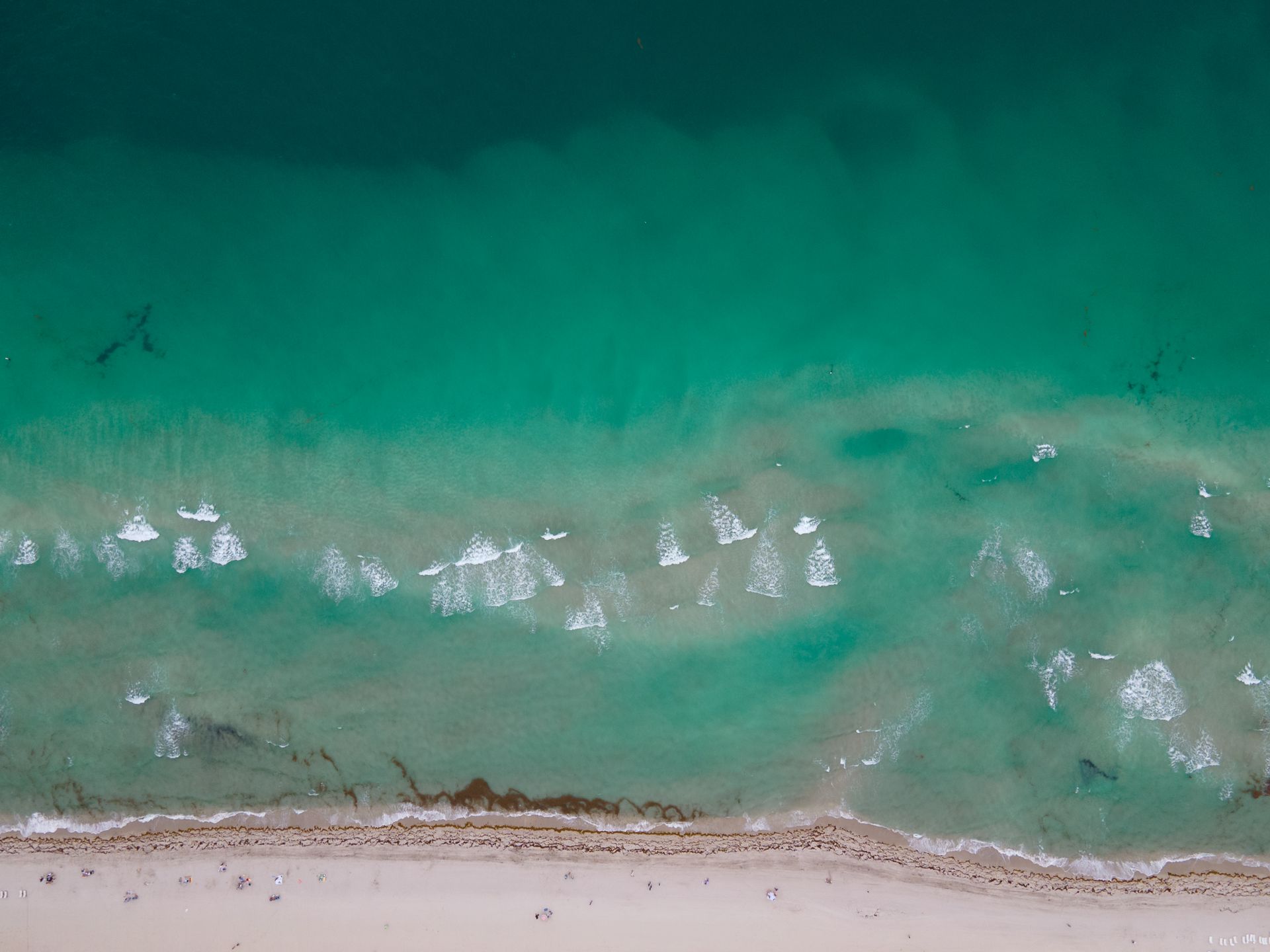 Explore the stunning turquoise waters and sandy beach of Miami from a breathtaking aerial perspective.