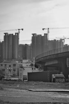 Black and white photo of urban skyscrapers under construction with cranes.