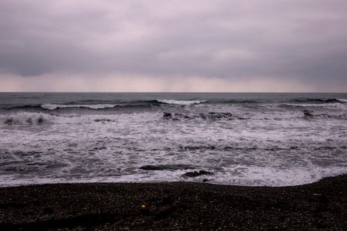 Free Capture of tumultuous waves crashing on a pebble beach under an overcast sky in Yangyang, South Korea. Stock Photo
