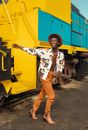 Boy in White and Red Floral Long Sleeve Shirt and Brown Pants Standing on Train Rail
