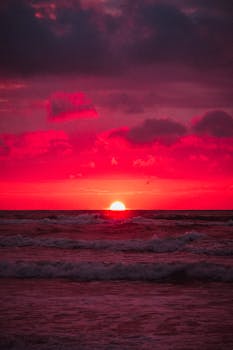 Vibrant red sunset over ocean waves creating a dramatic seascape.
