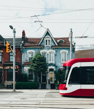 一辆红色有轨电车穿过多伦多街道，沿途可见经典的维多利亚时代建筑