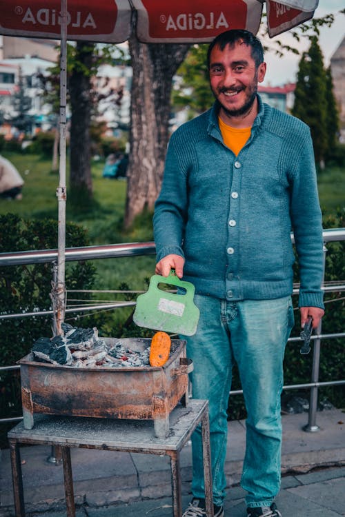 Man in Blue Sweater Holding Green Plastic Fan