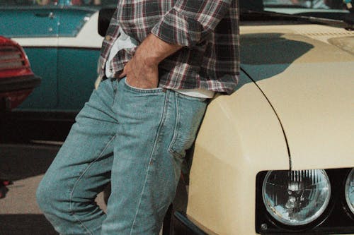 Person in Plaid Long Sleeves and Blue Denim Jeans Standing Beside the Car