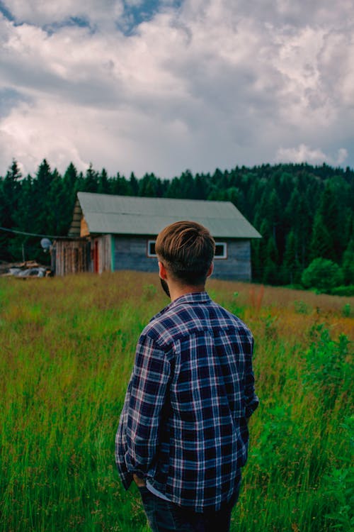 Man in Blue and White Plaid Long Sleeve Shirt Standing on Green Grass Field