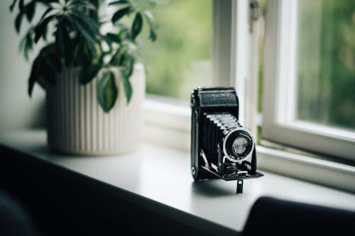 Kostenlos Vintage Folding Camera Sitzt Auf Der Fensterbank Stock-Foto