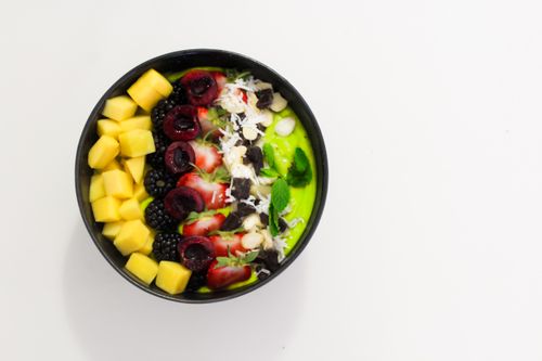 Free Delicious mixed fruit bowl with mango, blackberry, and cherry atop a creamy base. Perfect for a healthy diet. Stock Photo