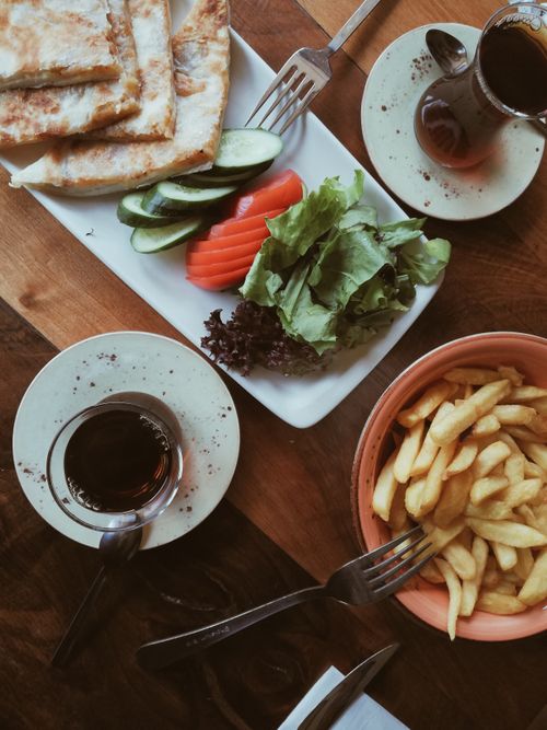 Free Savor a delicious Turkish brunch with tea, vegetables, flatbread, and fries on a wooden table. Stock Photo