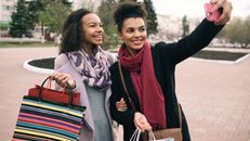 Happy Girlfriends with Shopping Bags Making Picture on Cellular