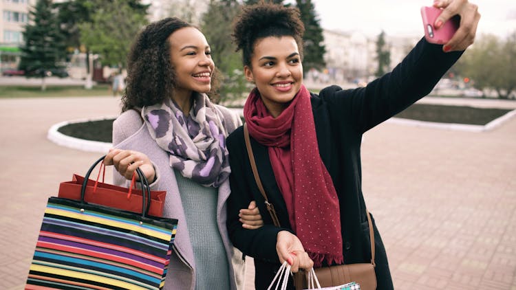 Happy Girlfriends With Shopping Bags Taking A Selfie