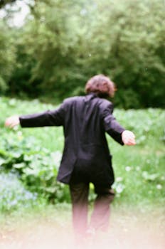 Motion blurred image of a man in a field, blurred background, natural setting.