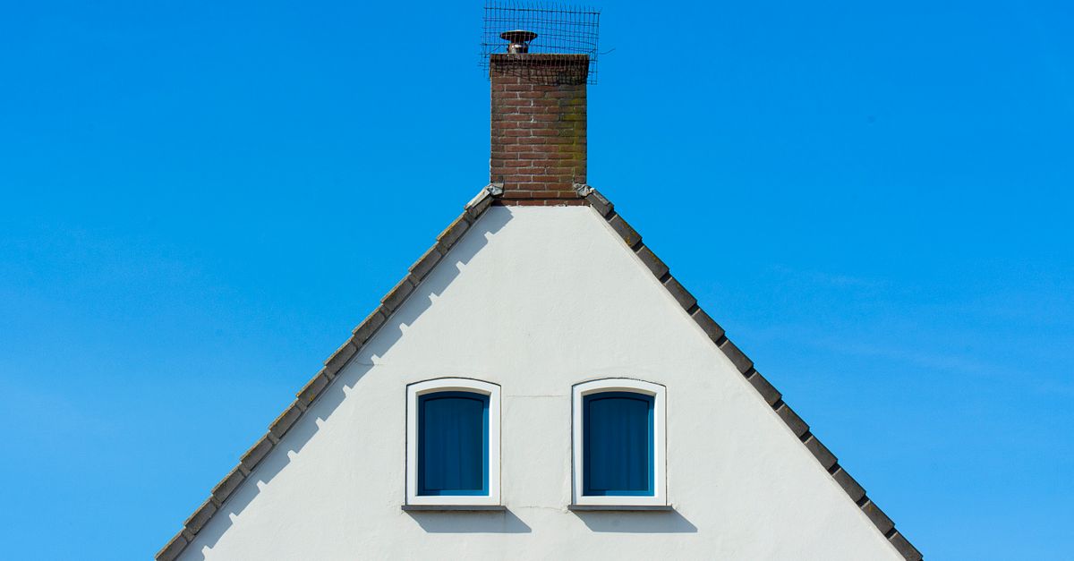 A minimalist house facade with a chimney against a bright blue sky, showcasing symmetry and simplicity.