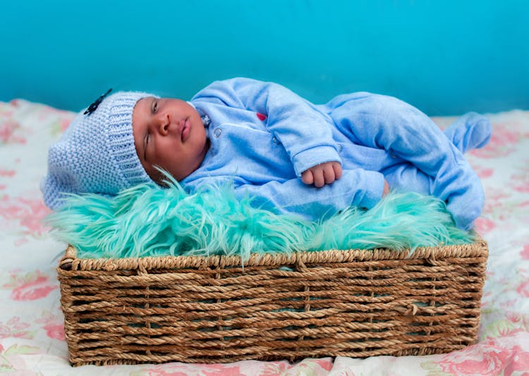 Baby In Blue Onesie Sleeping On The Woven Basket 