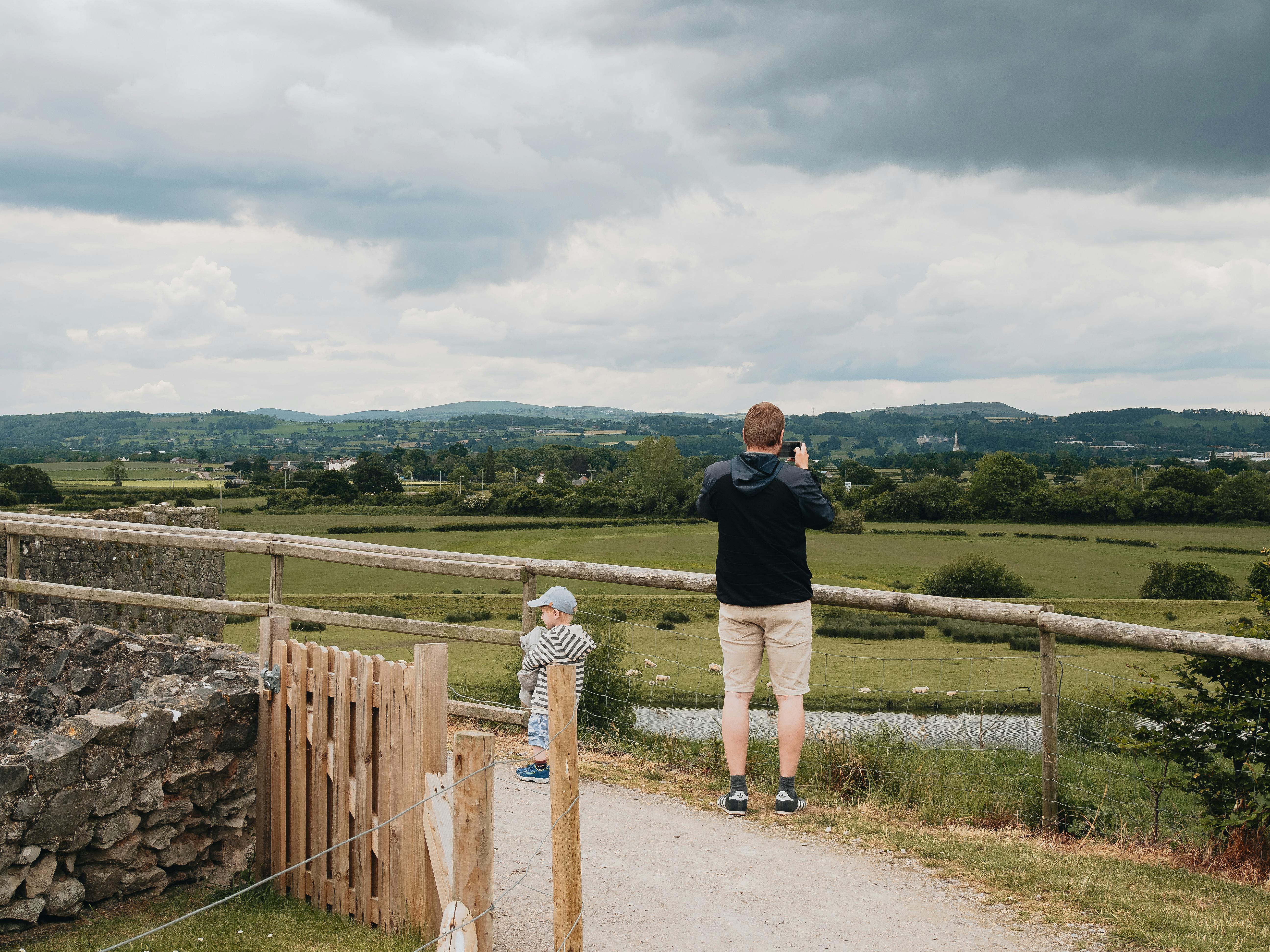 A father and son enjoying a scenic view in Rhuddlan, Wales on a cloudy day.