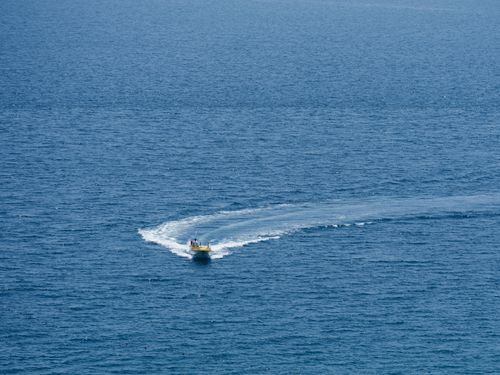 Free Aerial view of a speedboat making waves in the open ocean on a sunny day. Stock Photo