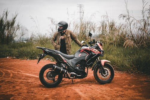A Man Holding a Motorcycle on the Dirt Road