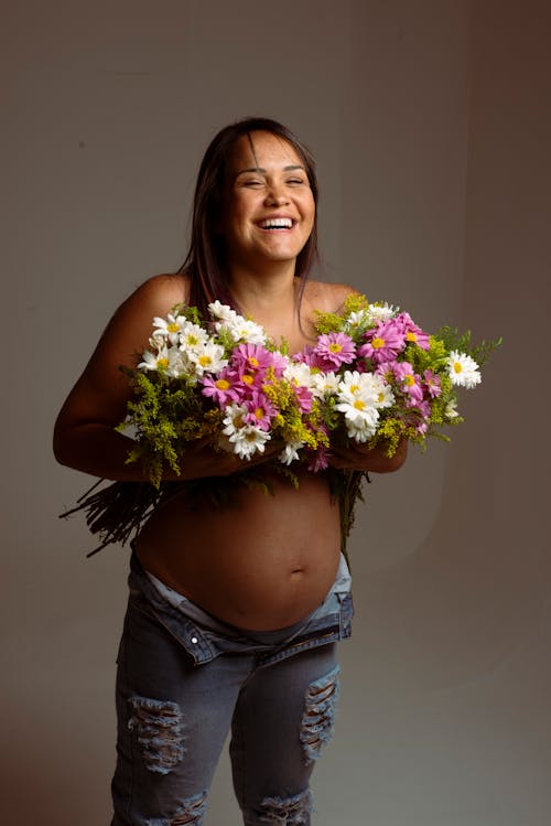 Pregnant Woman Covering Her Breast with Bunch of Flowers 