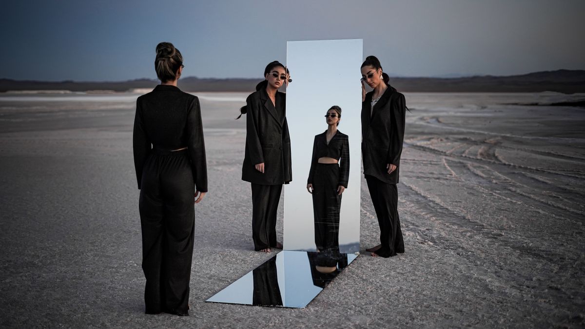 Portada de la demo de Ombra: cuatro modelos con trajes negros y un espejo en un salar