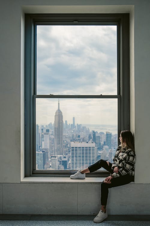 Woman Sitting in a Window and Looking at the City