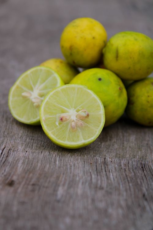 Free Vibrant close-up of sliced and whole lemons on rustic wooden surface, showcasing freshness. Stock Photo