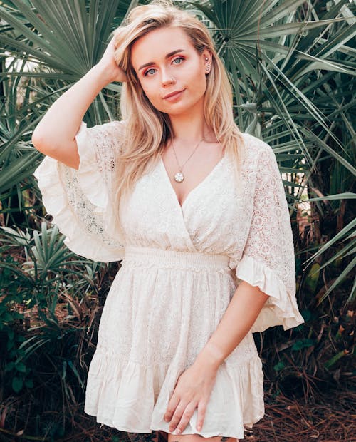 Woman in White Lace Dress Standing Near  the Green Plants