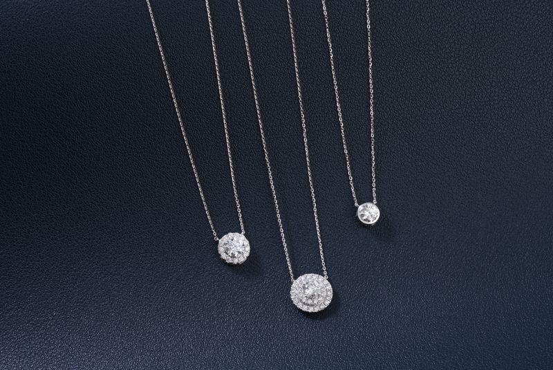 Three luxurious diamond necklaces elegantly displayed on a textured dark blue background
