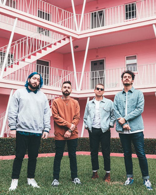 Group of Men Standing on the Green Lawn Grass in Front of the Apartment Building