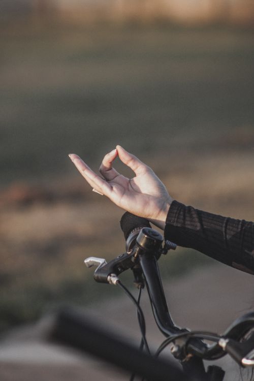 Free Close-up of a hand making a gesture on a bicycle handlebar outdoors, suggesting mindfulness. Stock Photo