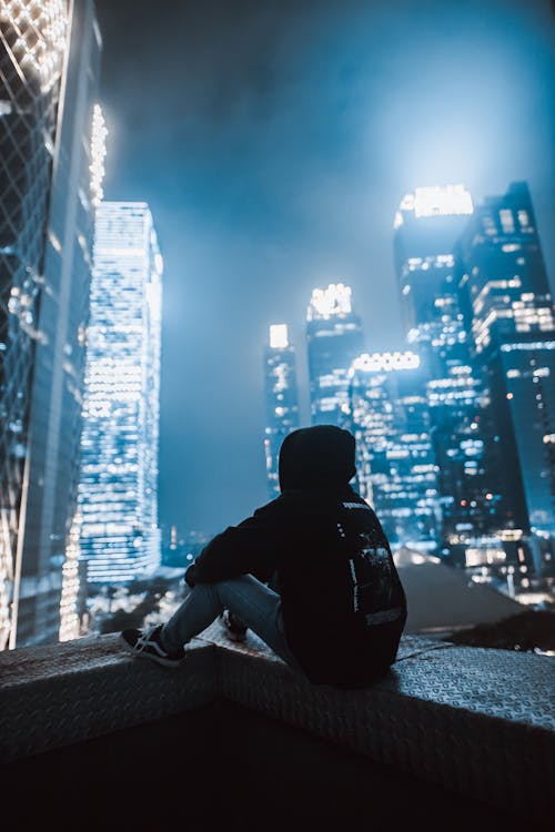 Man Sitting at Night on the Background of Illuminated Skyscrapers 