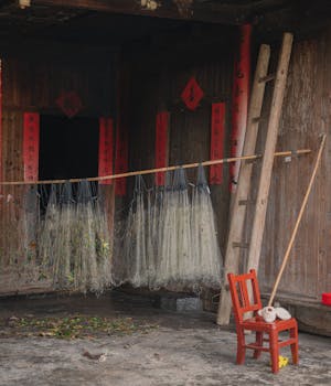 Traditional wooden house scene with fishing nets, a ladder, and a red chair.