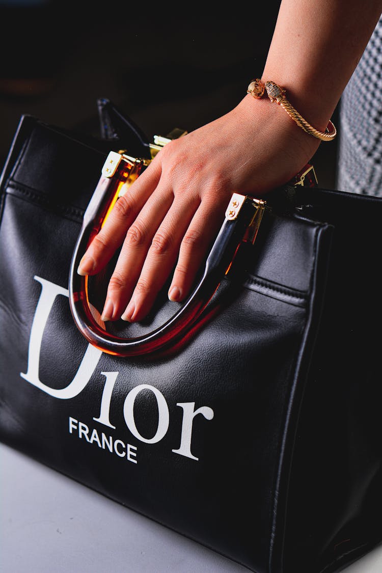 Hand Holding A Black Leather Dior Bag