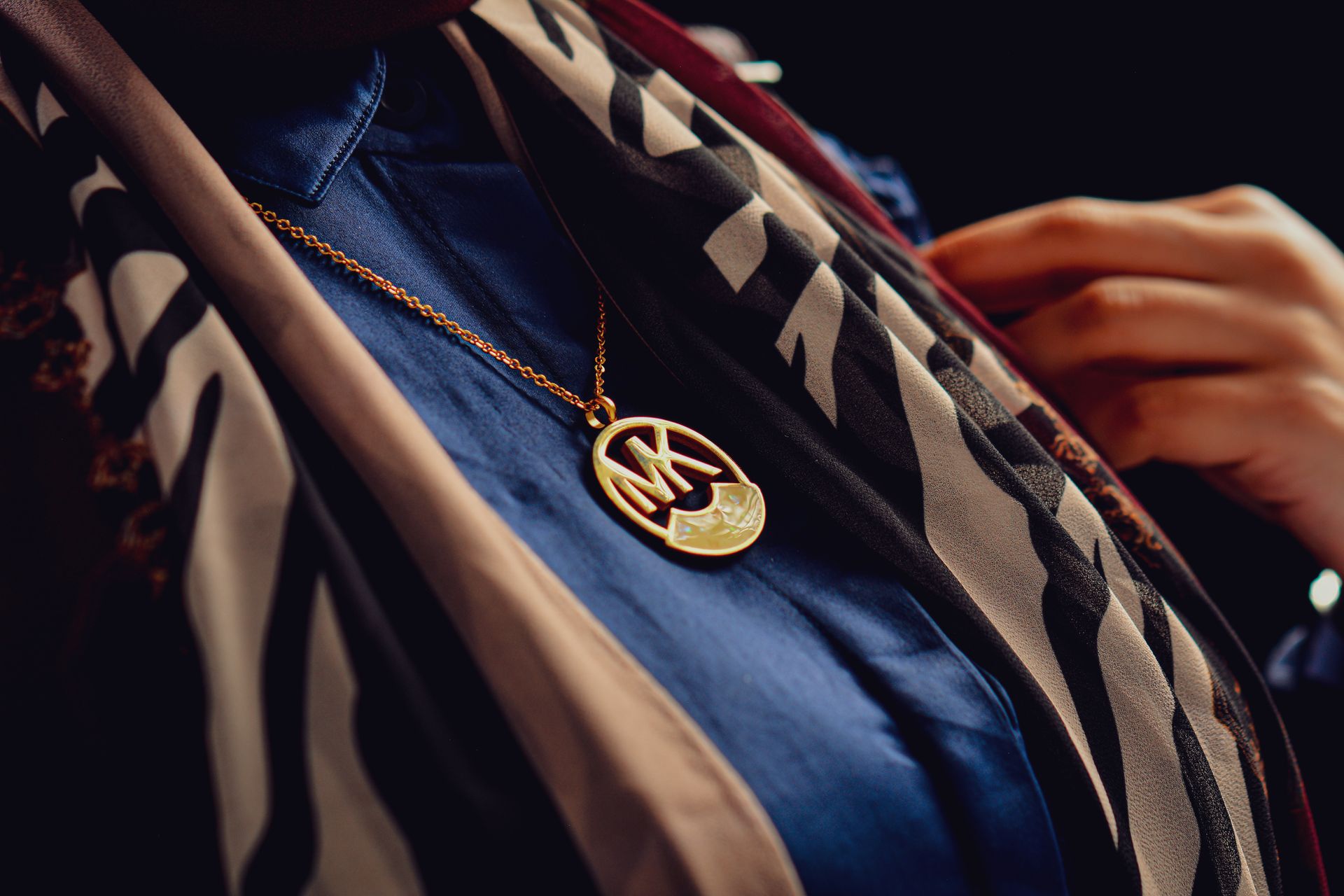 Close-up of a gold necklace with an initial pendant and patterned scarf.