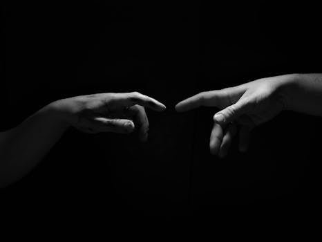 A compelling grayscale image of hands reaching out in a dramatic black background.