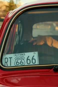 Close-up of a classic car window with a Route 66 California license plate.