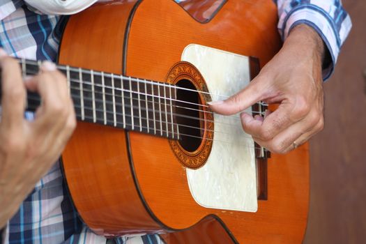 A detailed close-up of a flamenco guitarist's hands strumming a wooden guitar in Córdoba, Spain.. detailed, close, flamenco