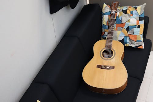 Brown Acoustic Guitar Leaning on Brown Velvet Couch · Free Stock Photo