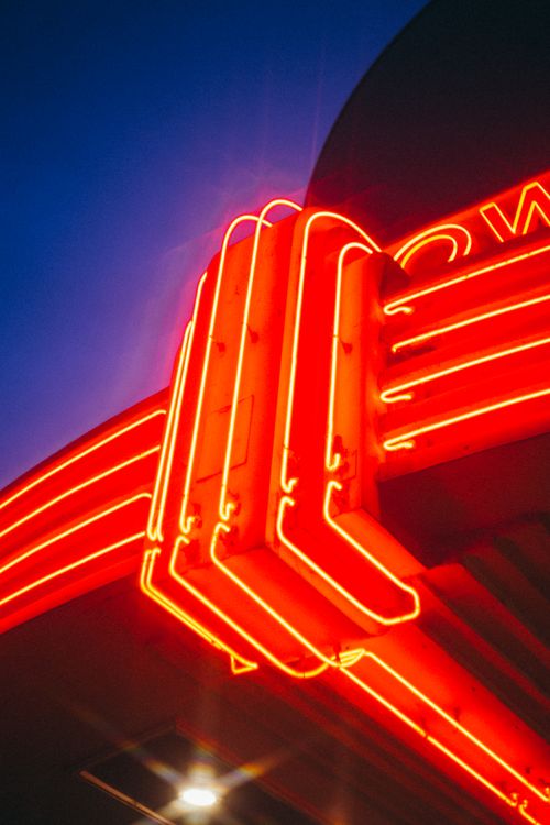 Free A striking neon red light display against a deep blue sky, showcasing urban nightlife. Stock Photo