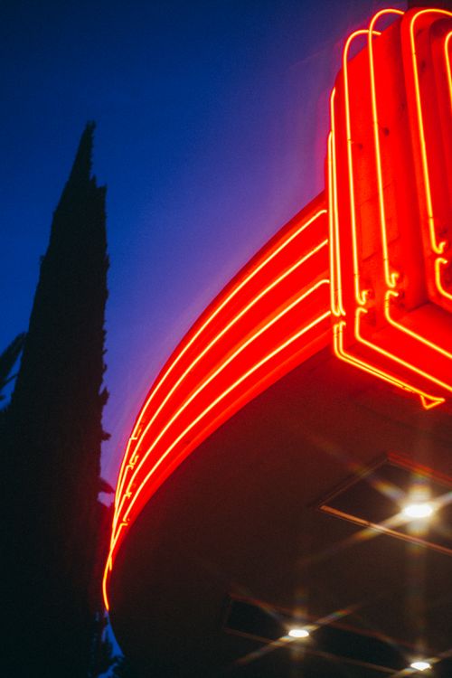 Free Bright red neon sign glowing against a deep blue night sky, capturing urban nightlife. Stock Photo