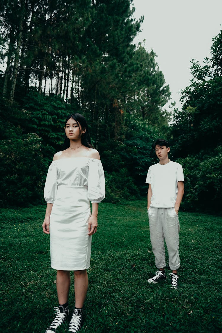 Two Young Fashion Models Standing In White Clothing In Park