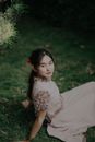 Girl in White Dress Sitting on Green Grass Field