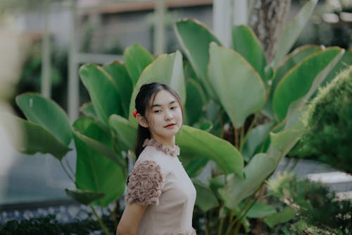 Girl in Beige Top Standing Near Green Plant