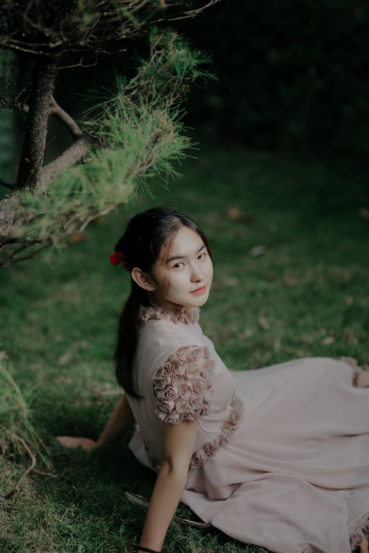 Pretty Girl Sitting On Grass And Posing For Photo