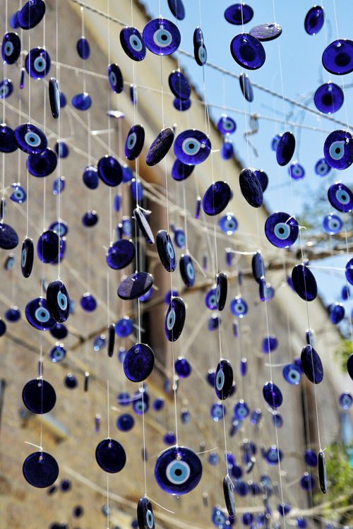 Free A vertical shot of numerous blue evil eye charms hanging outdoors in daylight. Stock Photo