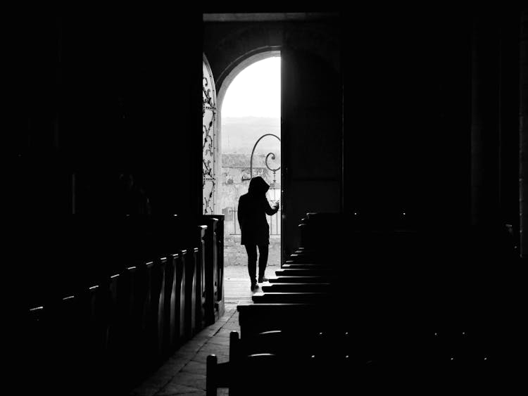 A Person Wearing Hoodie Opening The Door Of The Church